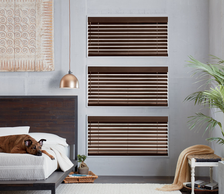 Bedroom with three windows covered with dark wood blinds from Hunter Douglas Denver CO