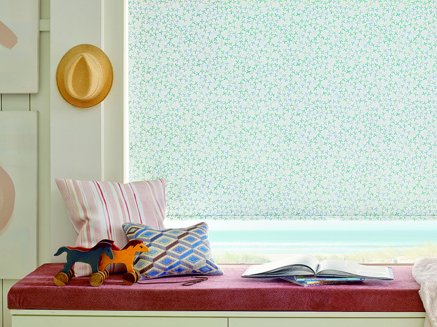 Floral roller shades above window seat.