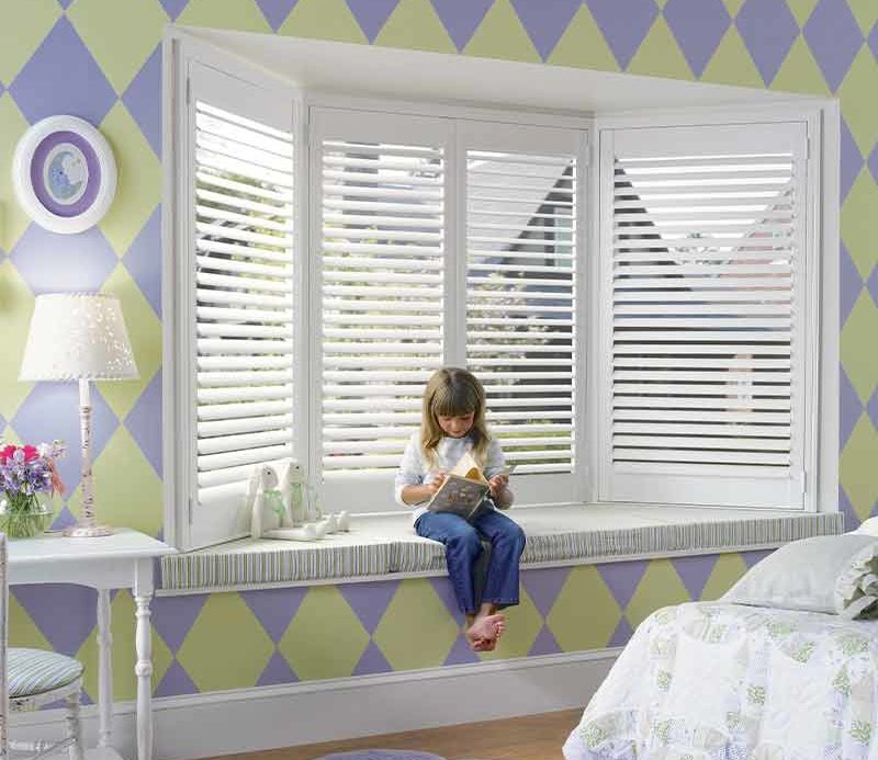 purple and green kids bedroom with white bay window shutters in Denver, CO