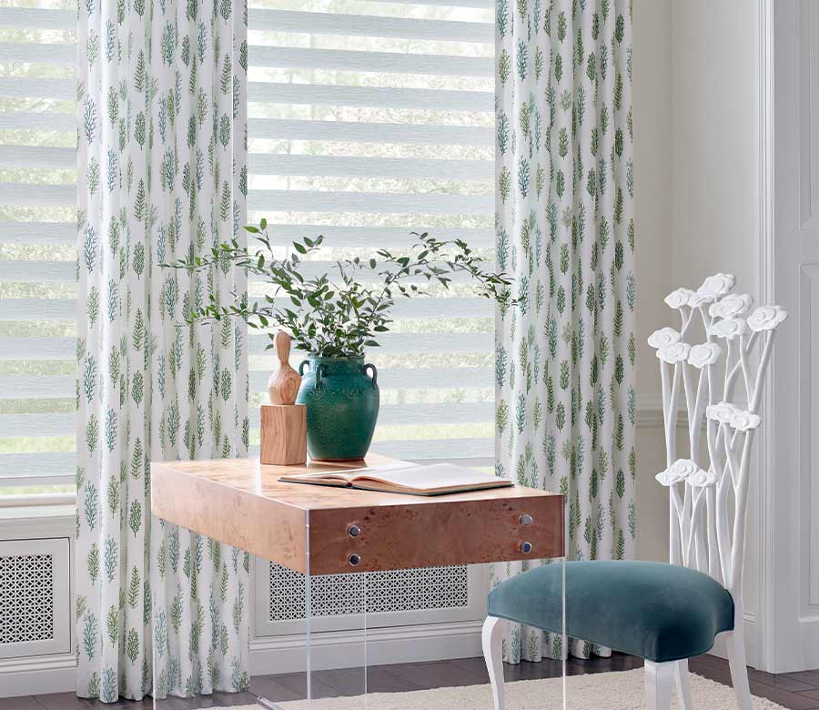 home office with banded dual opacity shades and floor to ceiling curtains with green and blue ferns