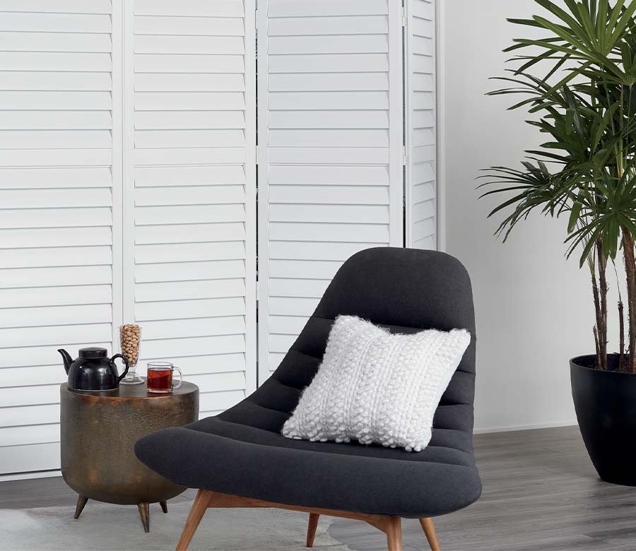 bi-fold custom white shutters behind lounge chair Denver, CO