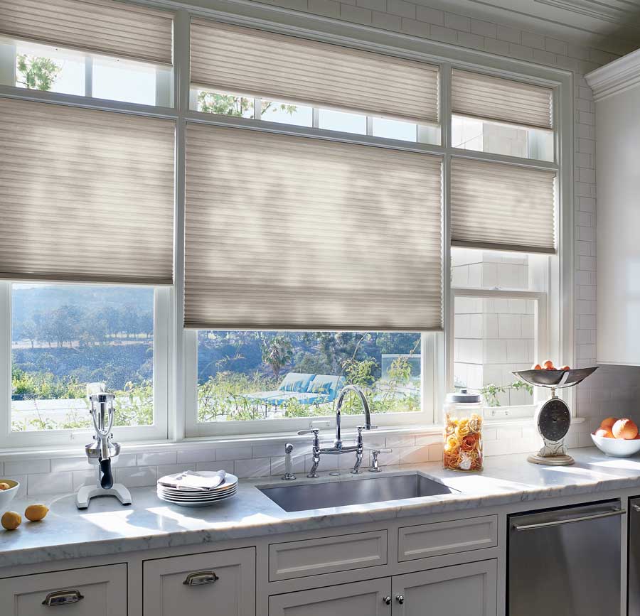 Light colored shades partially covering the windows above the kitchen sink.