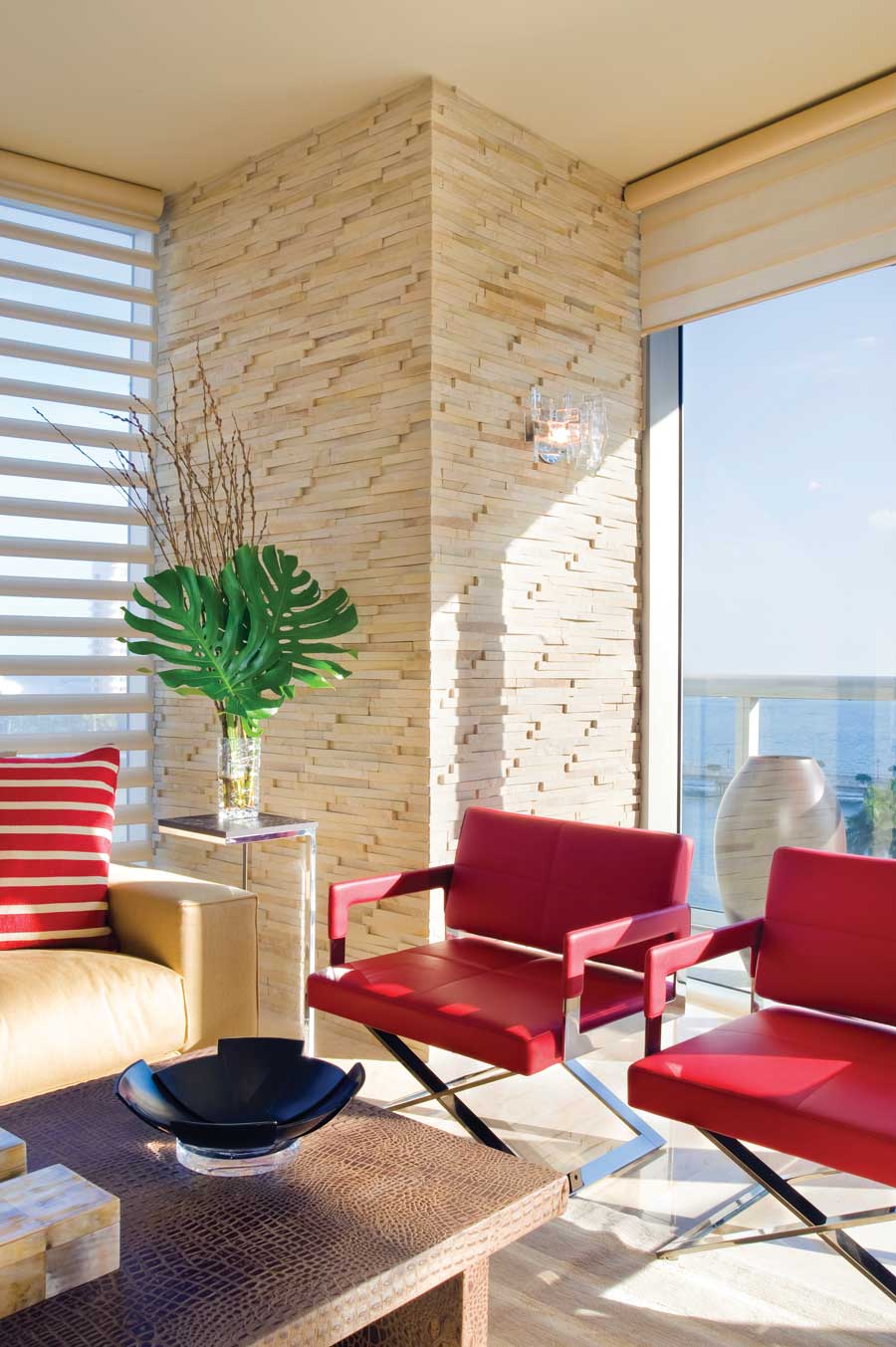 Neutral living room with red leather chairs and a red pillow on the couch