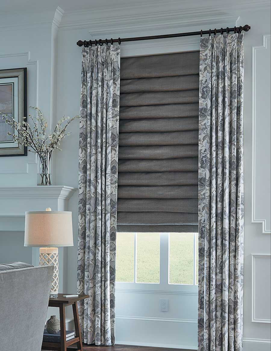 drapery and roman shades in layered fabrics at the window in Denver home