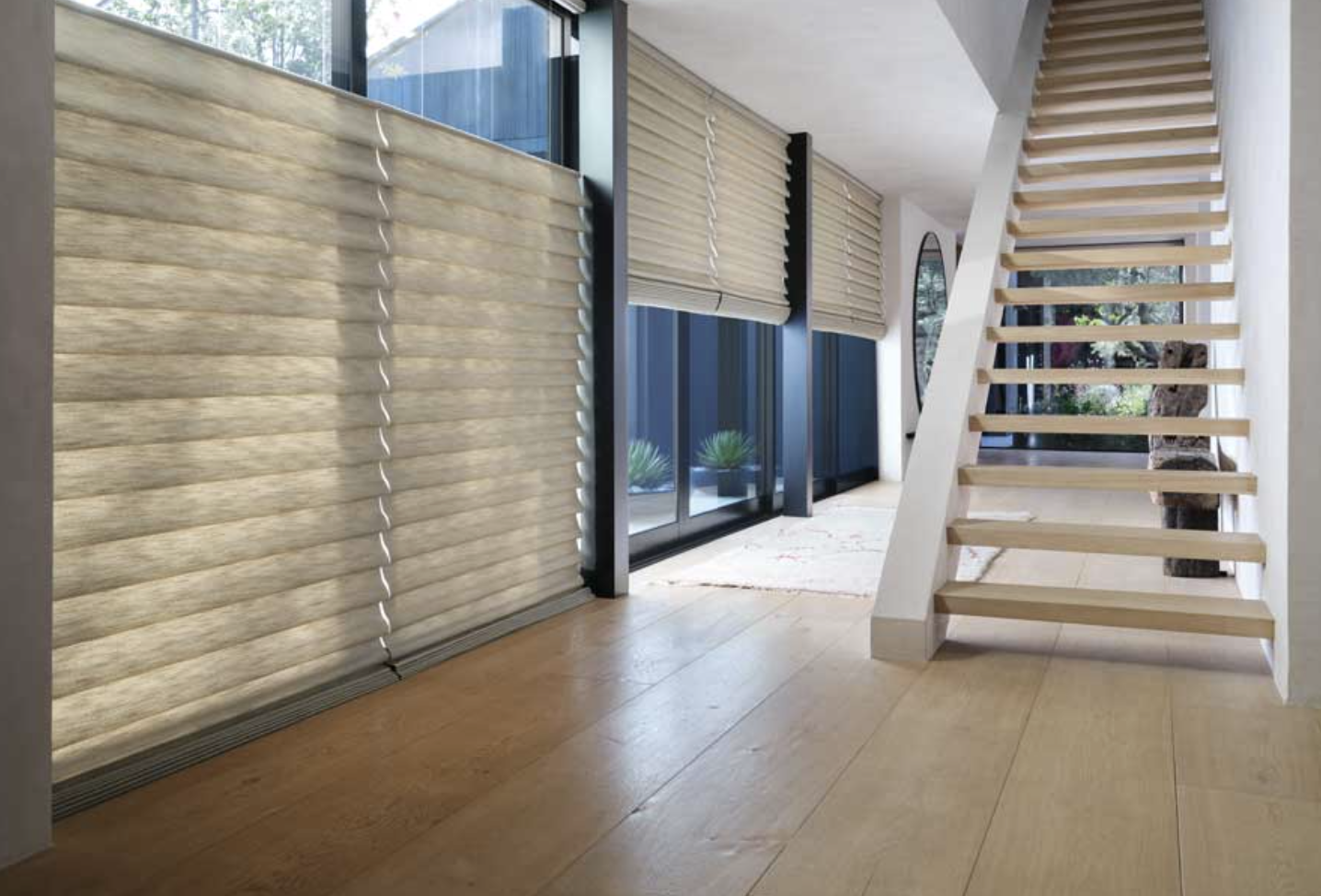 Vignette Modern Roman Shades covering floor to ceiling black trim windows in a long hallway that has a staircase on the right.