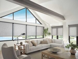large living room with angled windows, covered with gray roller shades on black trim