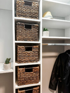 front closet with closet system installed with hang bar and woven baskets