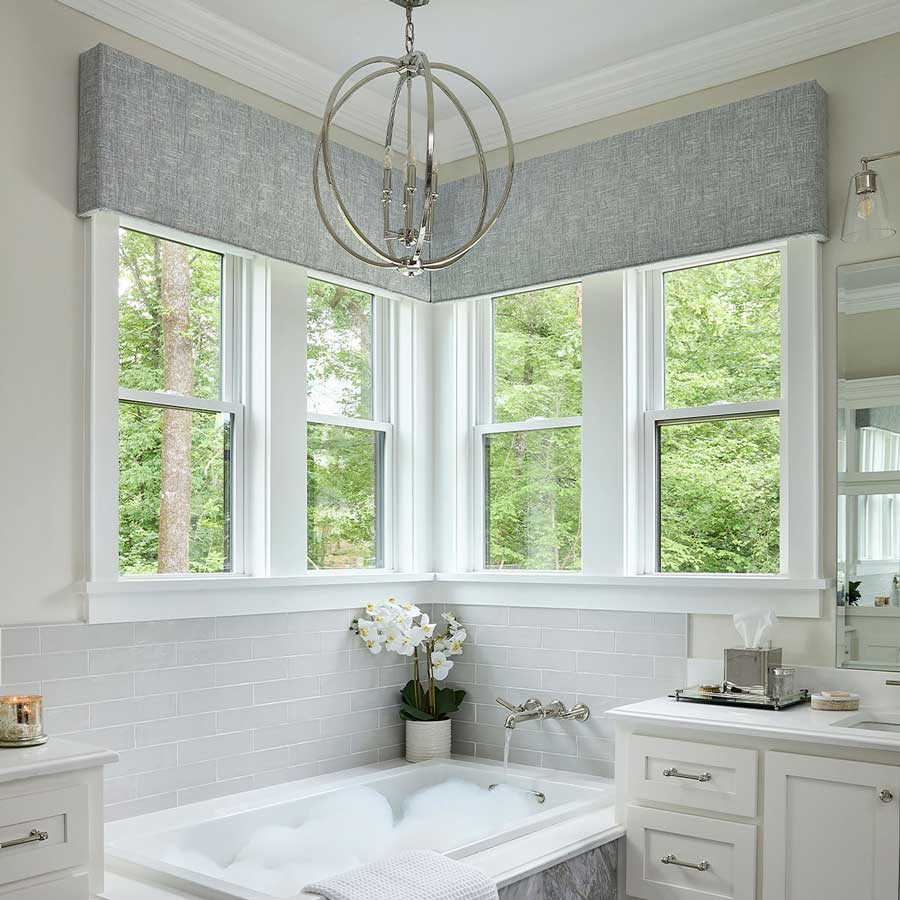 Gray cornices in the bathroom with two windows coming together in the corner of a bathroom above a bathtub