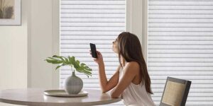 woman sitting using an app to control her window blinds in her kitchen
