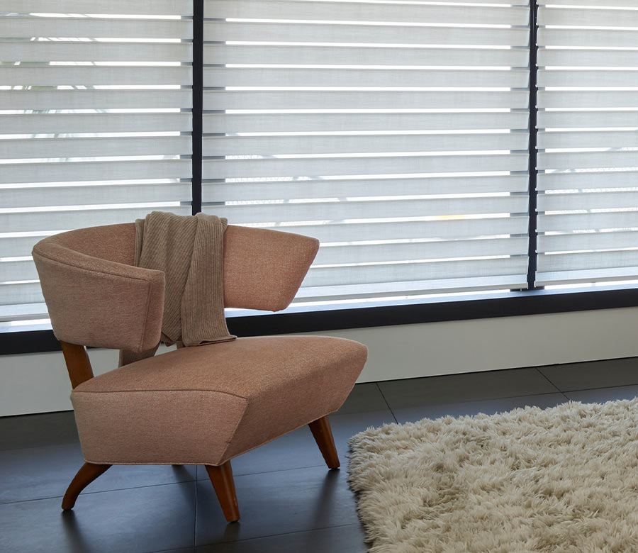 Silhouette® sheer window shades filtering daylight behind a modern accent chair for soft light control