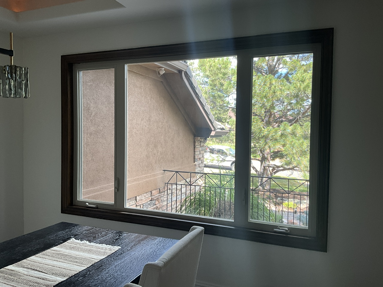 Dining room before window treatment installation with uncovered windows creating glare and limited privacy