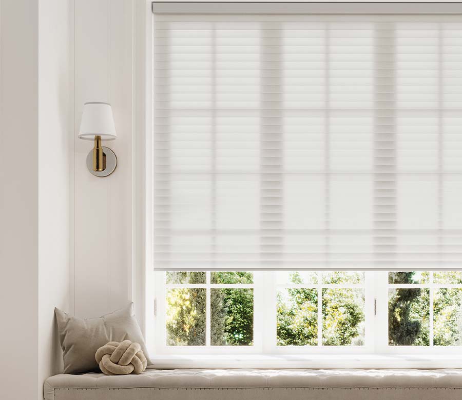 Light-filtering white cellular window shade above a built-in window seat in a bright living room